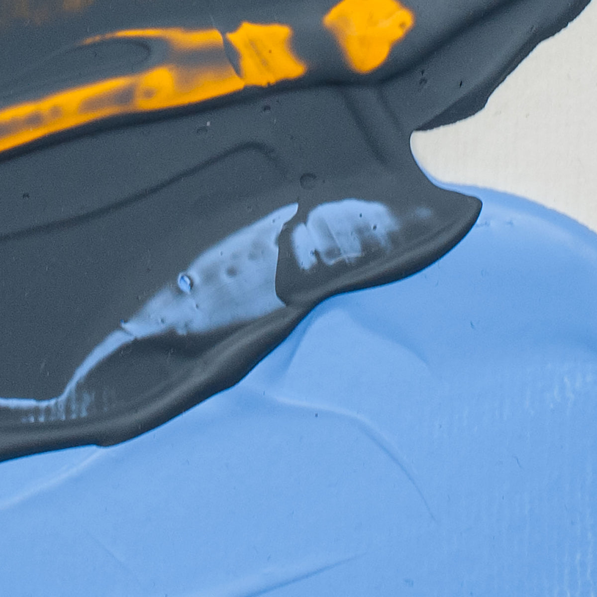Abstract close-up of thick paint with a large light blue area, a dark charcoal/black layer above it, and bright orange accents.
