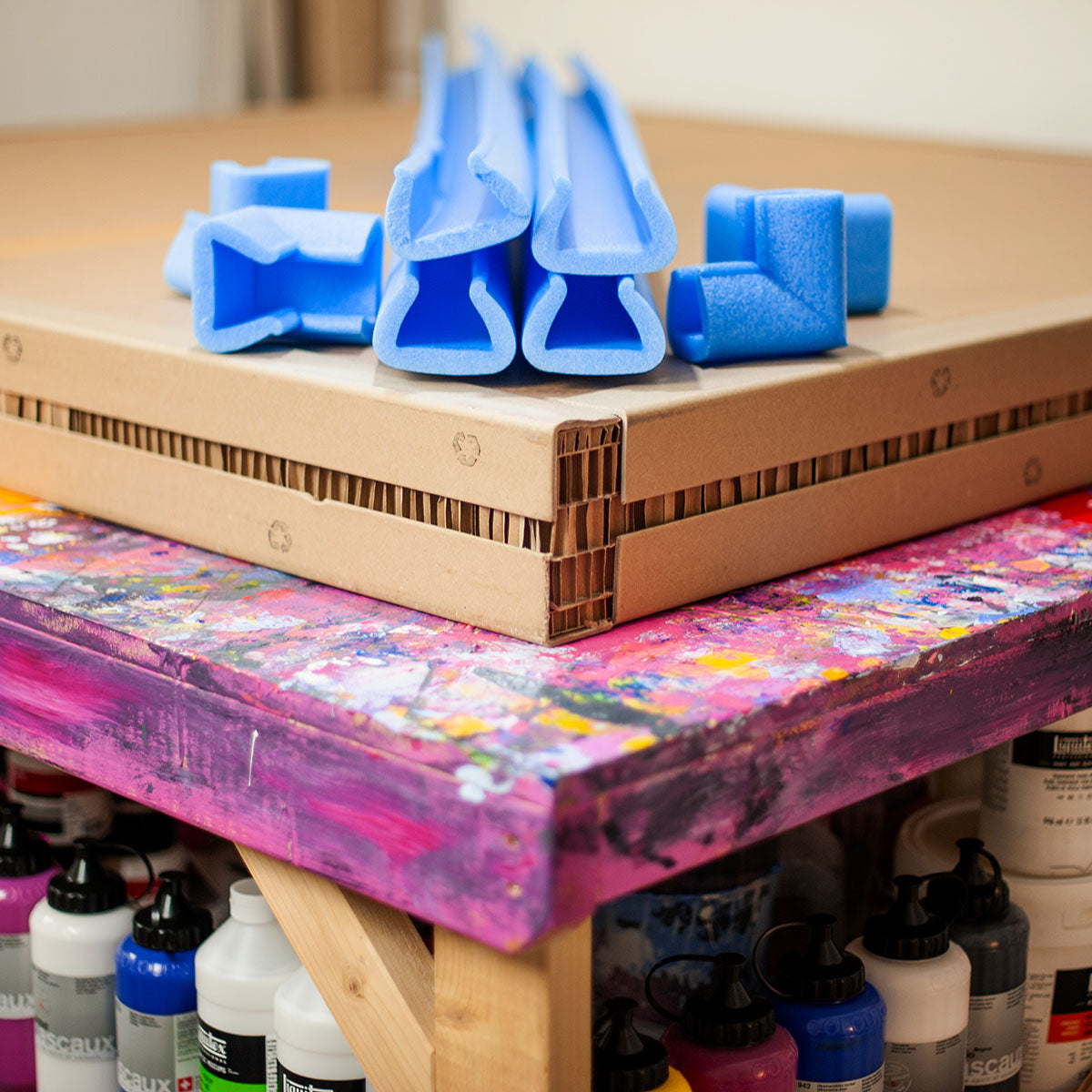Custom honeycomb cardboard boxes and blue foam protectors on a paint-covered workbench