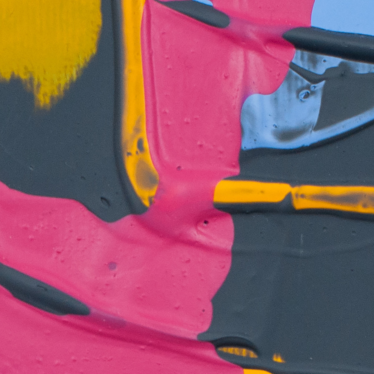 Abstract close-up of textured paint with large areas of bright pink, dark charcoal gray, yellow, and a small patch of light blue.