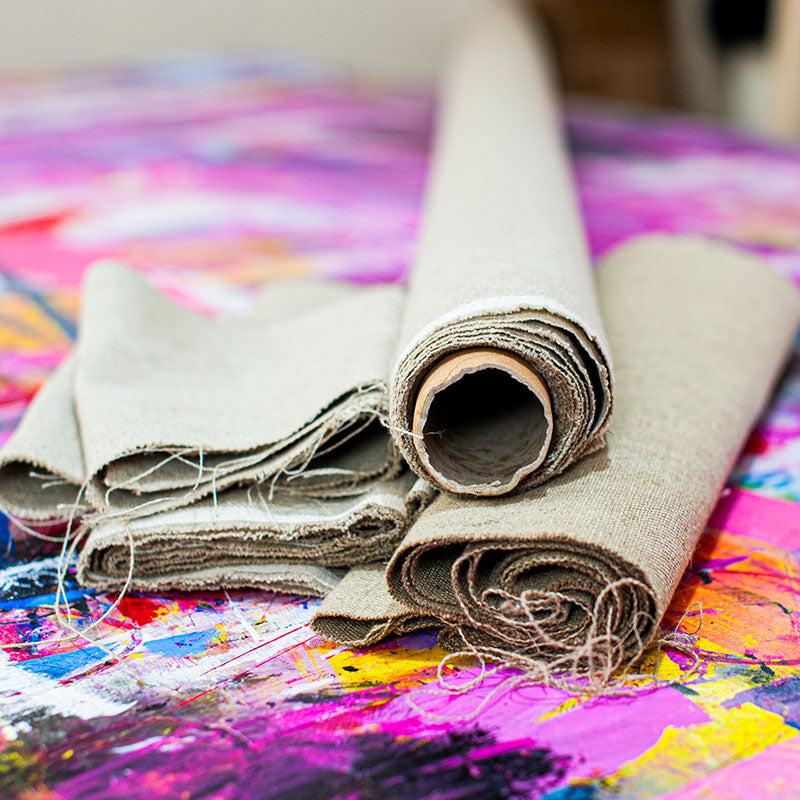 Rolled linen canvas on a colourful paint-covered workbench