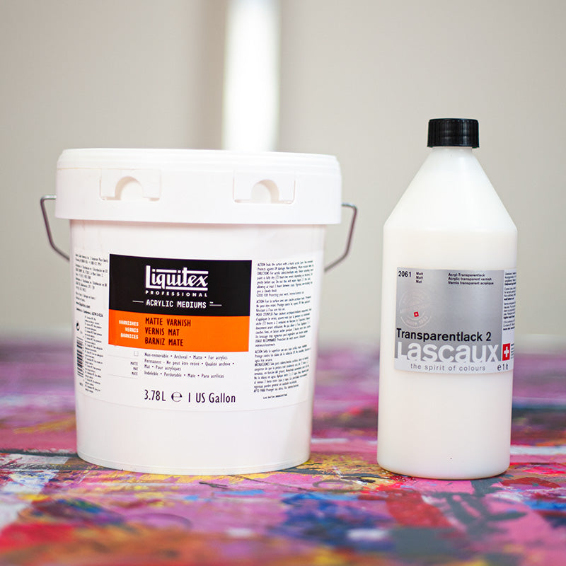 Liquitex and Lascaux matt varnish containers on a colourful paint-covered workbench