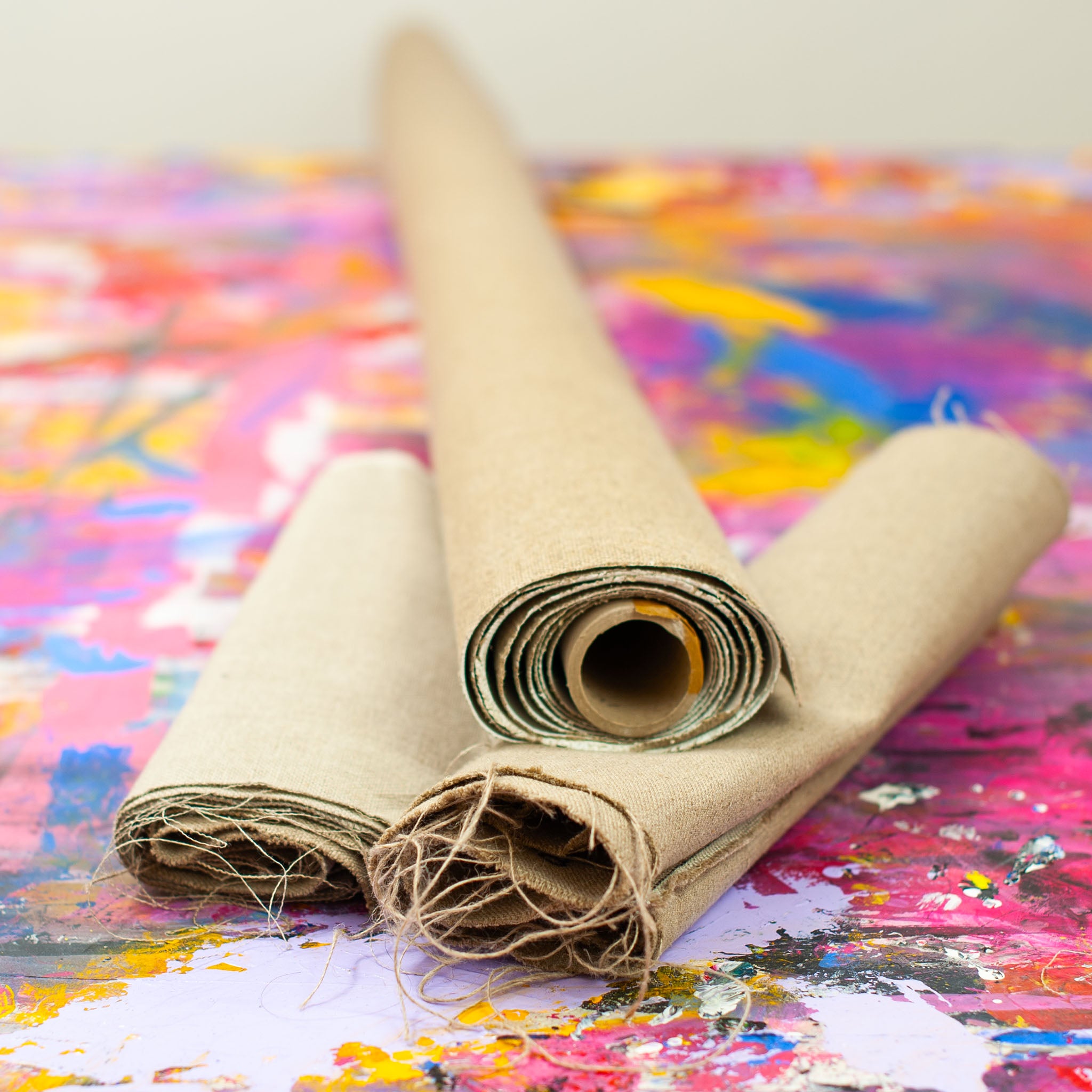Rolled artist linen resting on a paint-splattered studio workbench